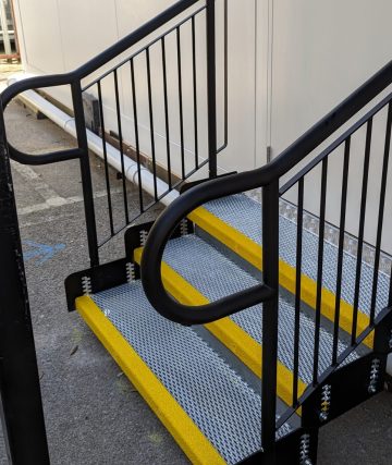 Black metal Step Units with handrails and optional fixing points, showing secure installation to provide added stability and safety at the entrance.
