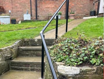Continuous handrail installed along outdoor steps, providing smooth, uninterrupted support up the pathway.