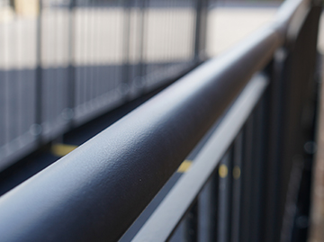 A close up image of a black, round, handrail.